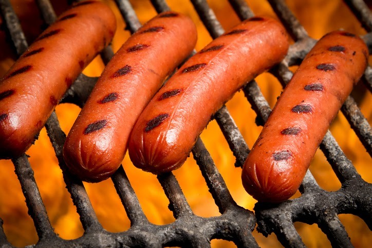 Four hot dogs with grill marks on the grill