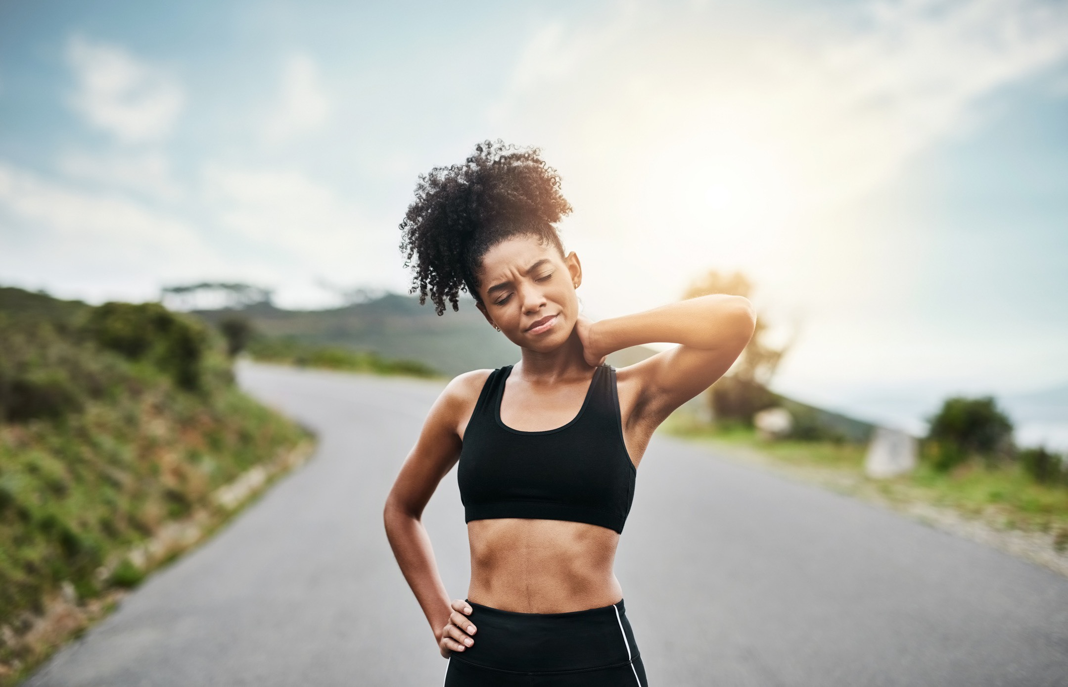 Woman on a run stopping to rub her neck